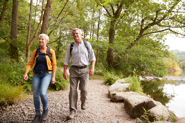 An older couple walking on a path alongside a lake