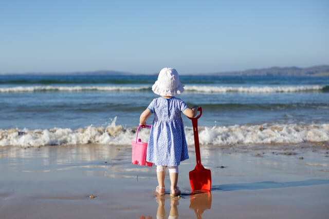 Little girl on the beach with a bucket and spade