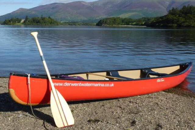 A red rowing boat on the shores of Derwentwater Marina