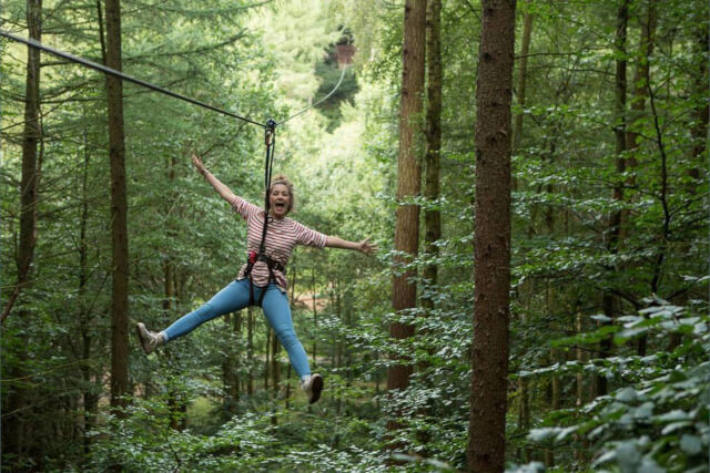 A woman ziplining through the trees