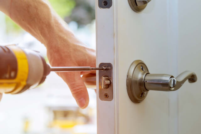 A locksmith using a drill on a door lock
