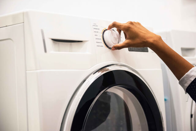 A handy twisting a dial on a washing machine