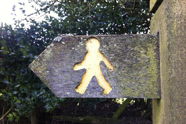 A wooden sign pointing left with an outline of a man walking