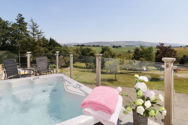 The view from a garden with a hot tub in the foreground and green countryside in the distance