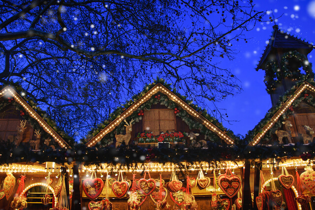Illuminated Christmas market wooden stalls at night time