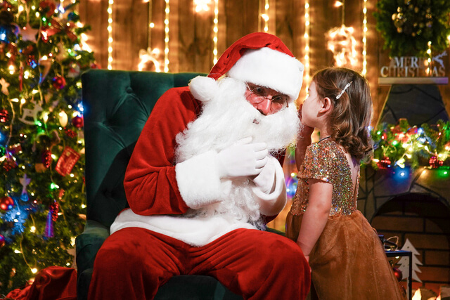 Little girl whispering in Santa's ear