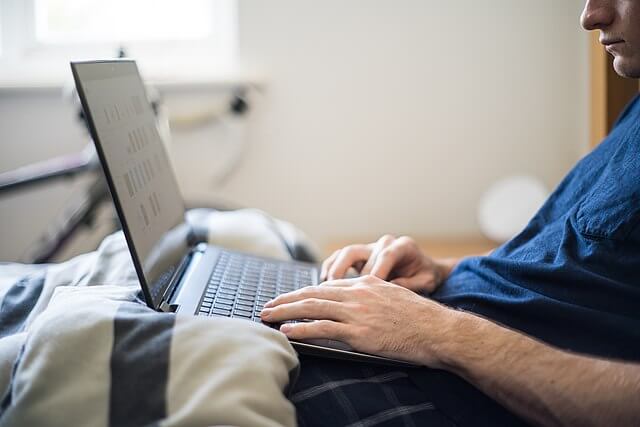 A man working on his laptop in bed