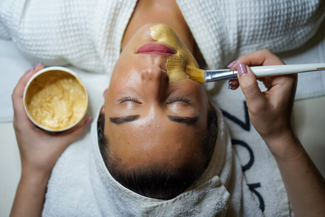 Woman having a facial mask painted on at a spa. 