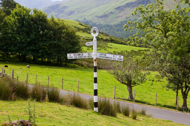 A black and white signpost surrounded by the green countryside in the Lake District