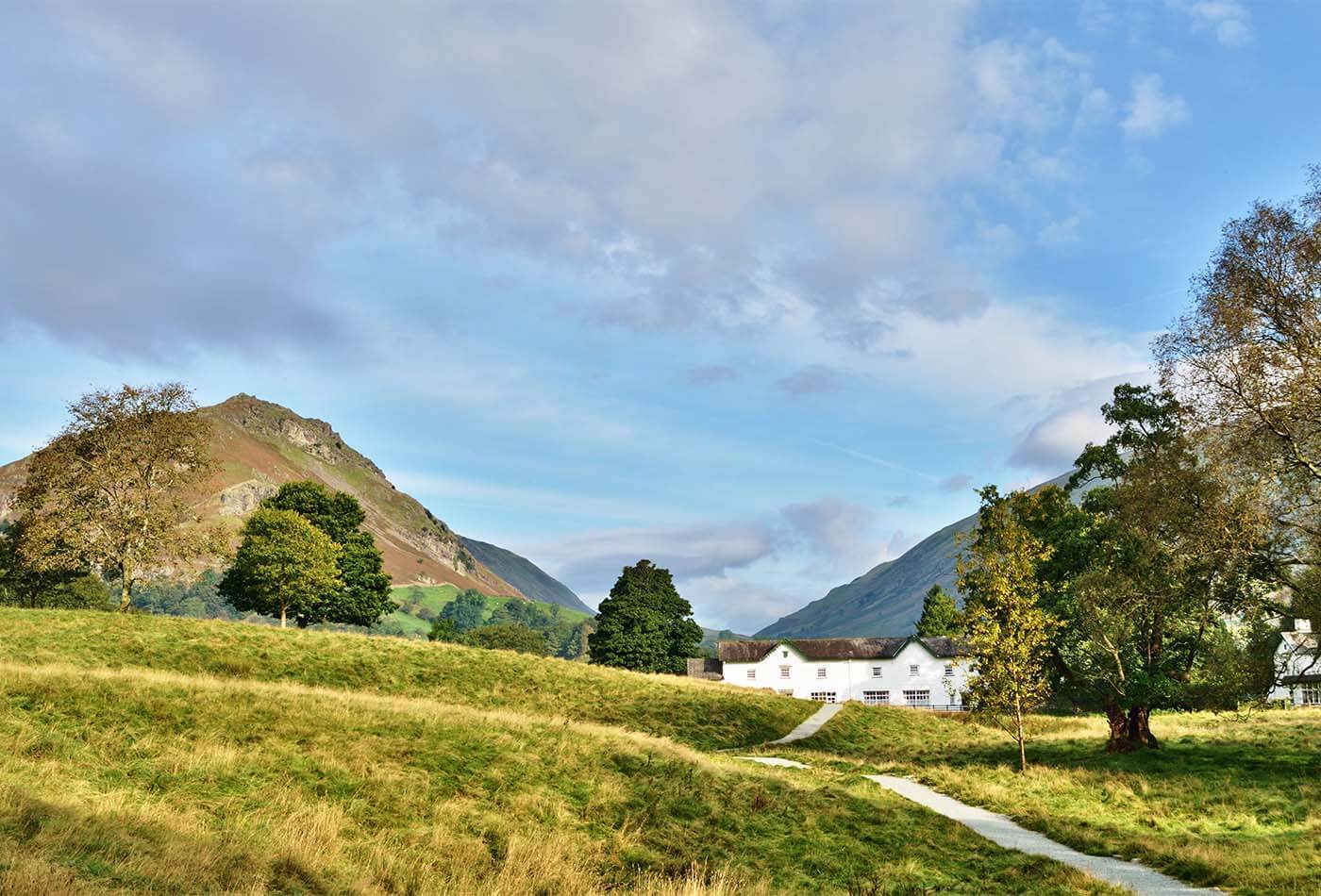 A white cottage sat amongst the green countryside of the Lake District