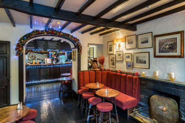 The traditional interior of the Badger Bar showing wooden beams bench seating and twinkle lights