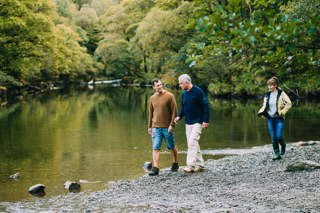 A family of three hiking along the shore of a lake in Cumbria