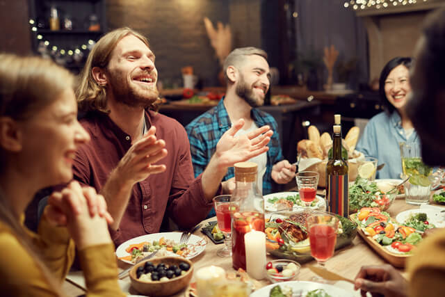 A group of young adults sat around a dining table laughing