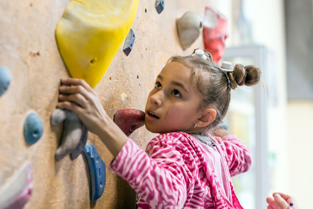 A little girl climbing an indoor climbing wall