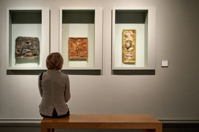 A woman sat on a bench looking at artwork on the wall in a gallery