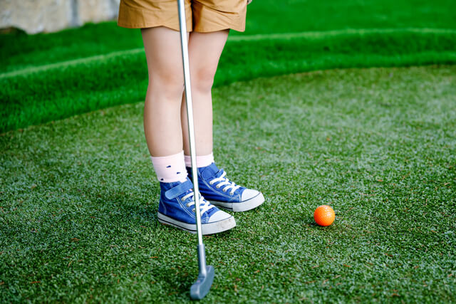 A young child playing mini golf