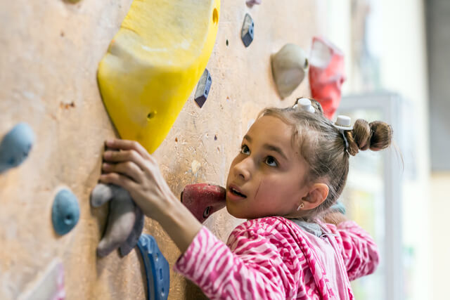 A young girl climbing on an indoor climbing wall