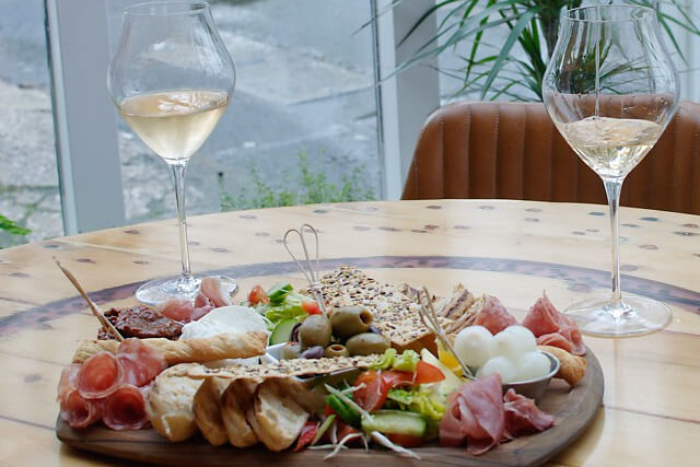 Charcuterie board and two glasses of white wine at The Windermere Speakeasy