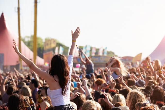 People with their arms in the air at a Summer music festival