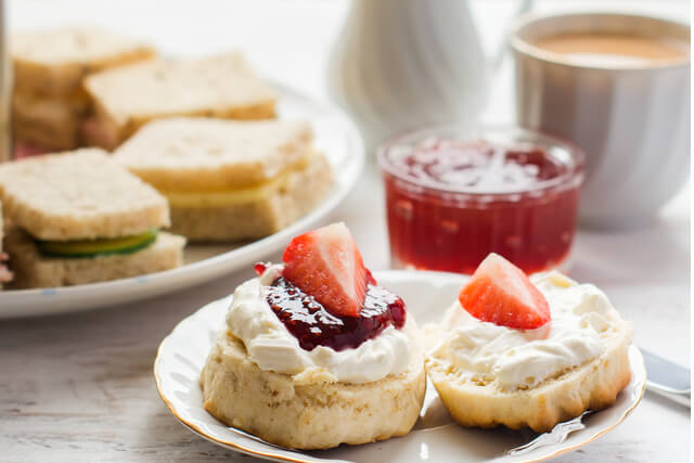 Scones with jam and cream served with sandwiches and a cup of tea