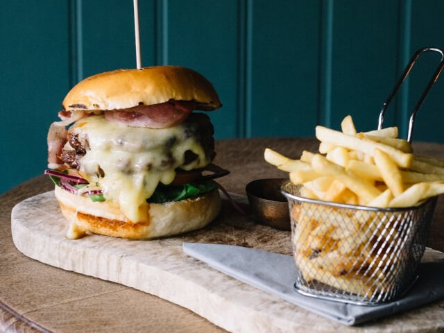 A big burger with cheese and a side of chips at The Flying Pig in Bowness 