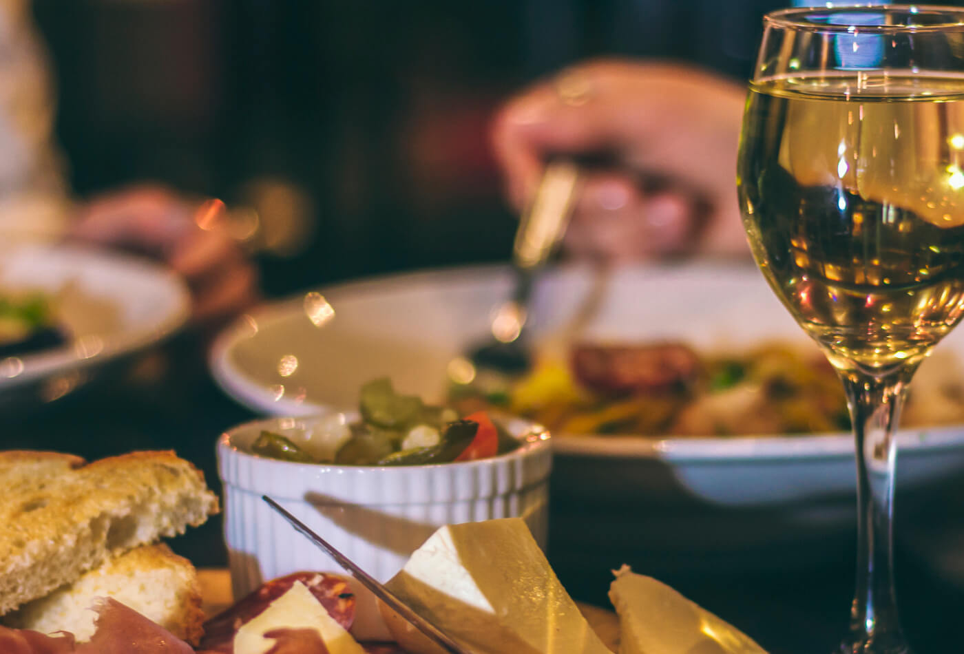 A glass of wine and a continental meat platter on a table