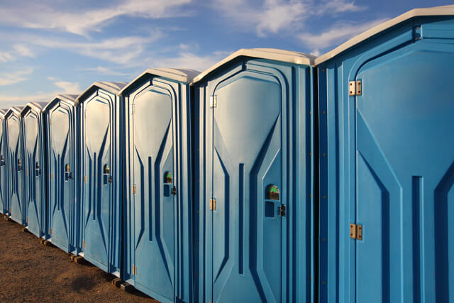A row of portaloos in a field at a festival