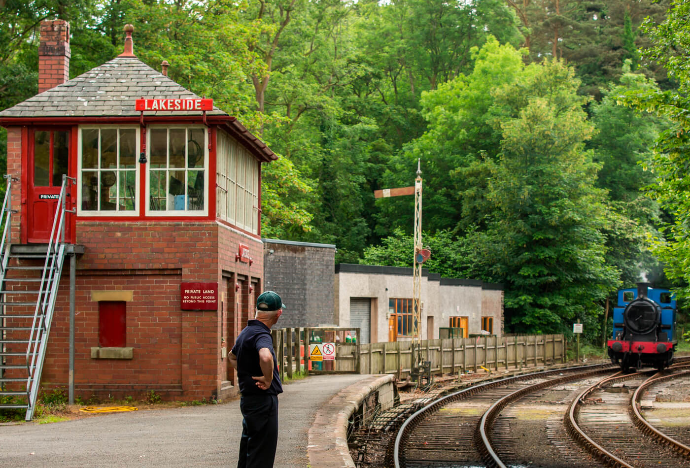 A conductor waiting for a steam train to arrive at Lakeside station