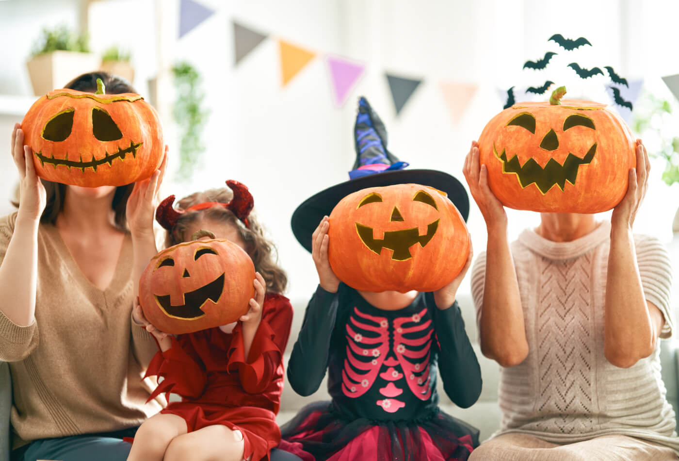 A family celebrating halloween with carved pumpkins covering their face