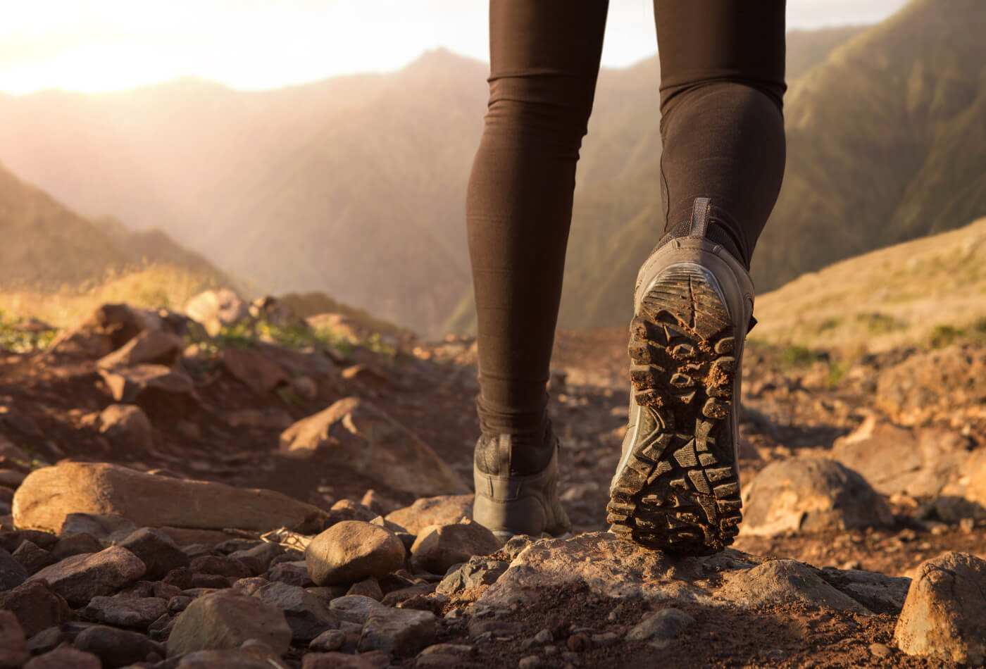 A woman wearing walking boots hiking along a stone path