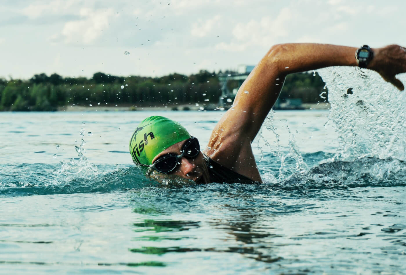 A man wearing a goggles and a swimming cap open water swimming