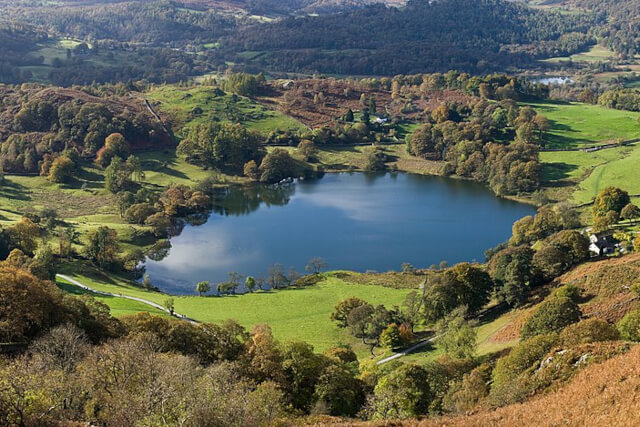 Loughrigg Tarn surrounded by green countryside and trees