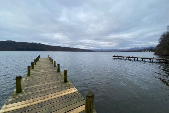 Two wooden jetties stretching into Lake Windermere below a stormy sky