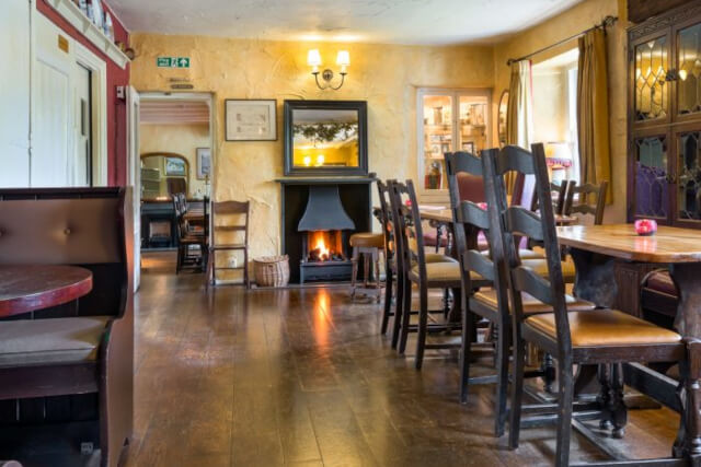 Internal shot of the wooden floor and furniture with a roaring fire at The Travellers Inn Grasmere