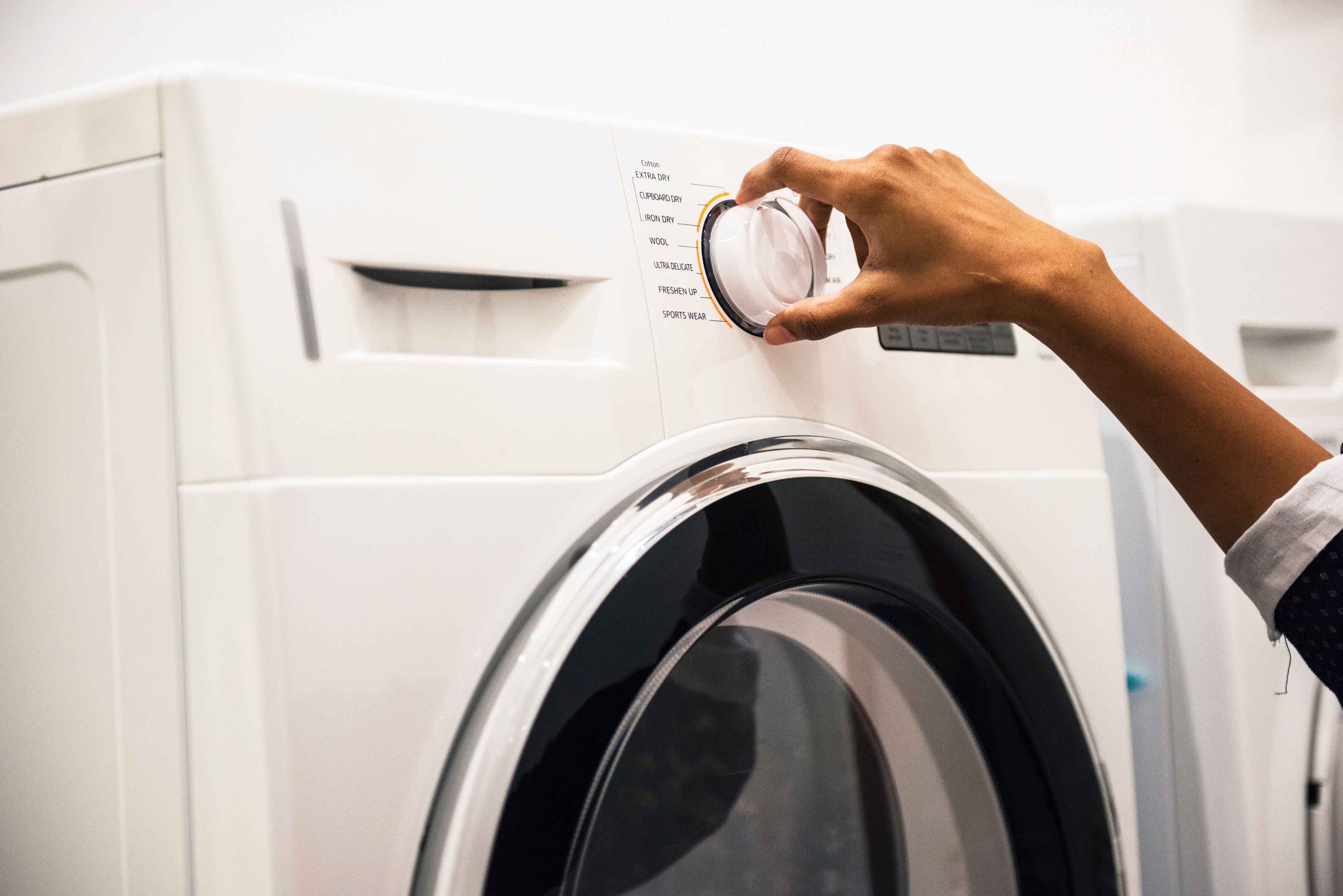 Person turning dial on washing machine