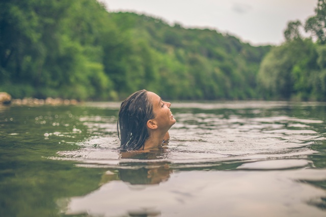 A person in the lake with trees in the distance